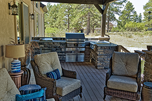 Outdoor living space with built-in grill and wicker furniture.