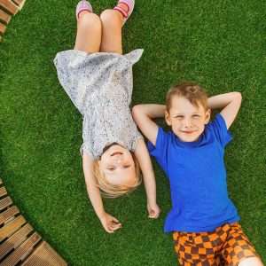 Overhead view of kids lying on a healthy green lawn, looking up at the sky.